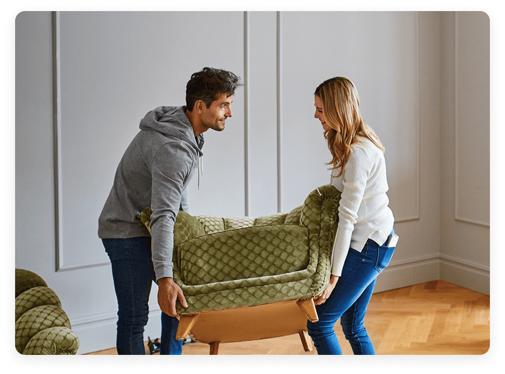 A couple moving a chair into their home